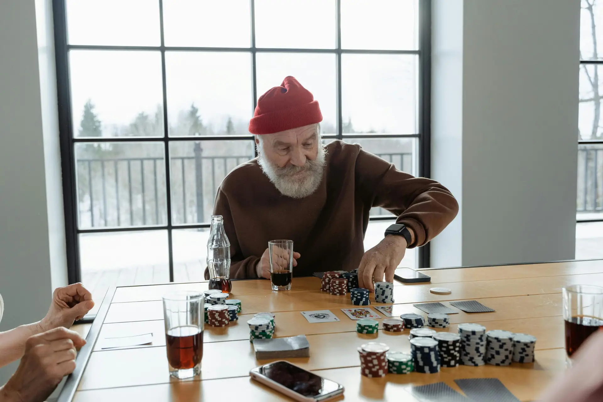 Elderly man playing poker at a table with friends, capturing a moment of enjoyment and strategy.